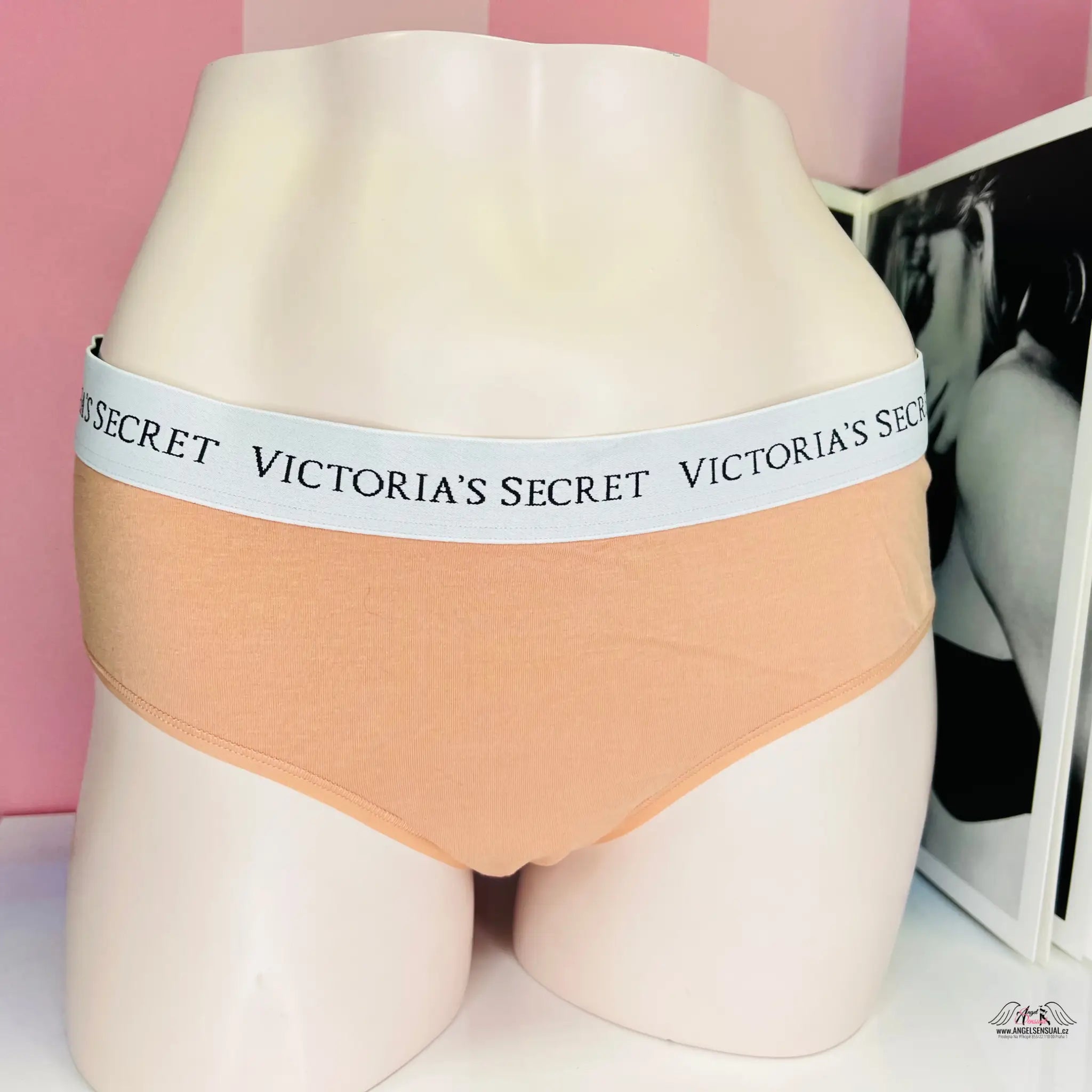 Spodní prádlo Victoria’s Secret broskvové barvy s elastickým pasem s logem na figuríně.