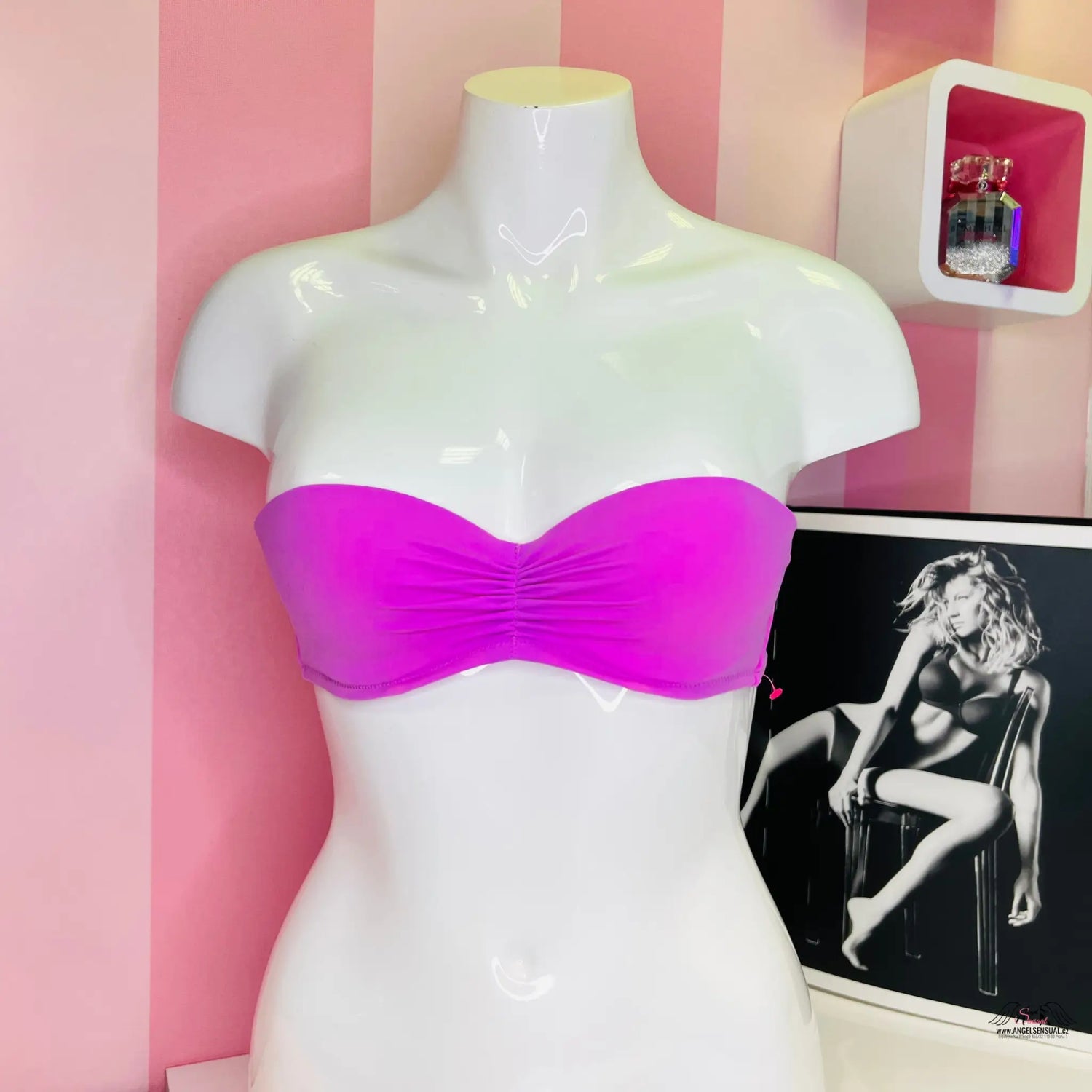 Sytě růžový bandeau bikini bez ramínek vystavený na bílém trupu manekýny.